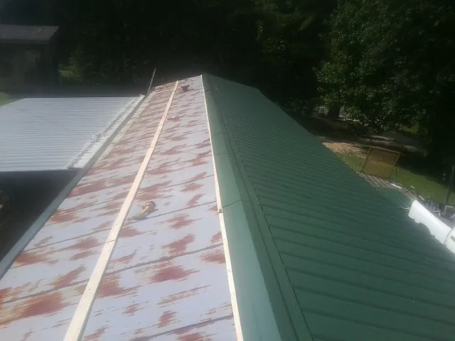 Old rusted panels beside newly installed green metal roofing — Wind Damage Roof Repair by Roofing Brothers in Grand Rapids