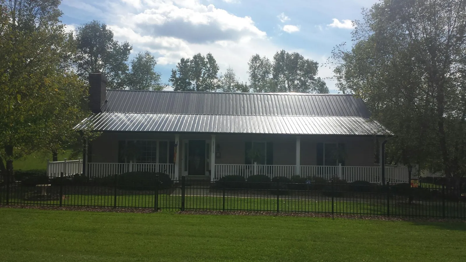 Gray metal roof on a brick ranch with a full width front porch — Gutter Guard Installation work by our crew in Grand Rapids