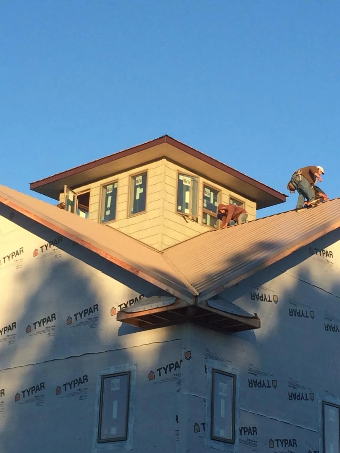 Roofers working around a rooftop cupola on a new metal roof at sunset — Roof Waterproofing in Grand Rapids by Roofing Brothers